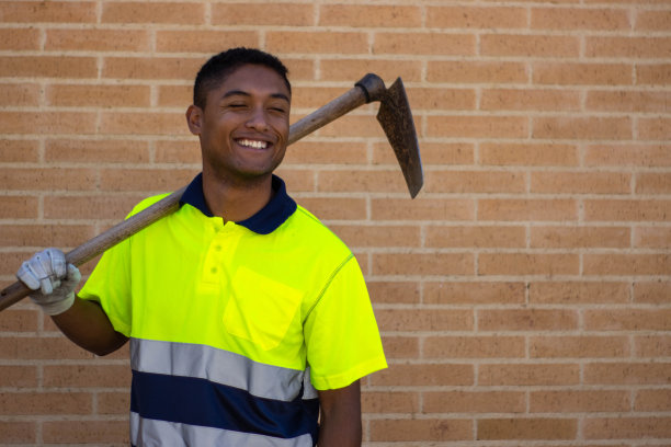一个微笑的工人的肖像，在他的肩膀锄头图片下载