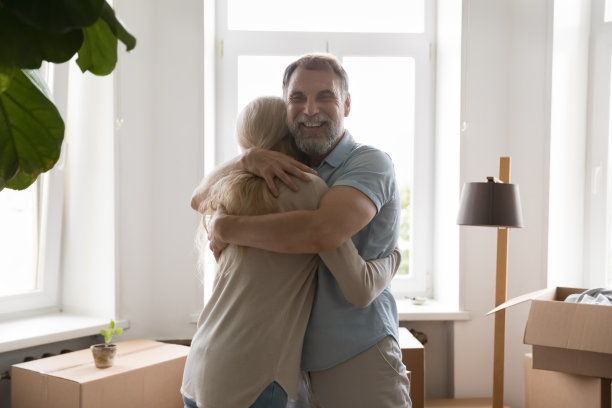 一对幸福的白发退休夫妇在室内移动的箱子间拥抱图片下载