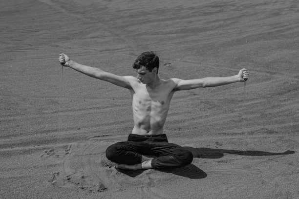 沙漠里，一个人坐在沙丘上，用手把沙子灌进去图片下载