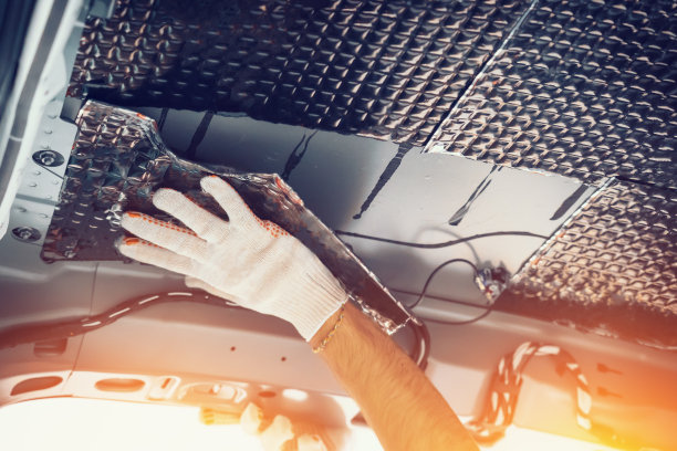 工人用手将隔音材料粘在车顶内侧。汽车隔音安装过程图片下载