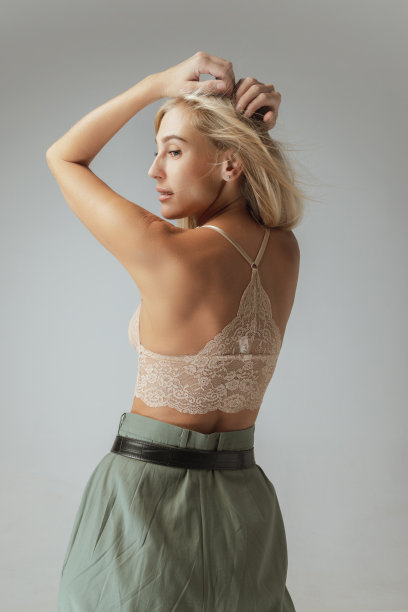 性感的年轻女子长直的金发蕾丝胸罩和休闲裤子摆姿势在灰色背景。时尚、美丽图片下载