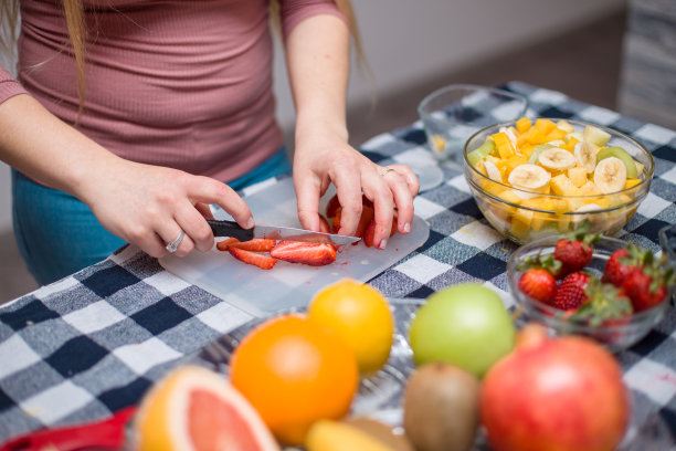 小女孩在做新鲜水果沙拉，切草莓图片下载