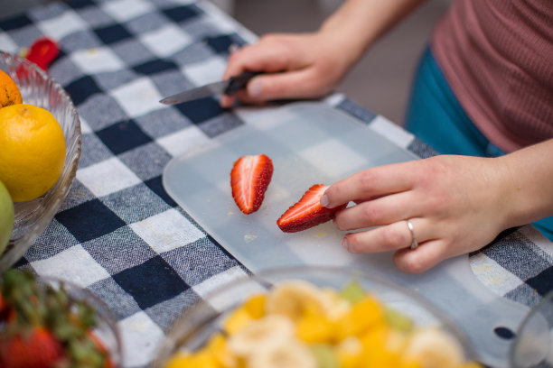 小女孩在做新鲜水果沙拉，切草莓图片下载