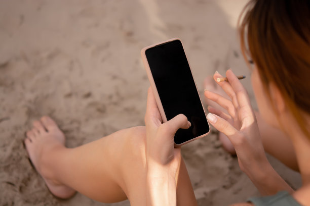 一个穿着运动服的小女孩手里拿着手机抽着烟，穿着绿色的运动服上衣和自行车短裤，水平衡，户外运动，运动的生活方式图片下载