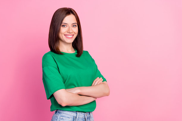 照片肖像的惊人的年轻女子交叉双臂目前的服务推动者穿着时髦的绿色服装孤立在粉红色的背景图片下载