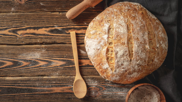 自制的天然面包，金色的面包皮在餐巾上，旧的木制背景。烘焙面包产品。乡村风格图片下载