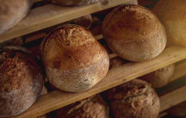 面包店的架子上放着刚烤好的圆形小麦面包，面包皮金黄酥脆图片下载