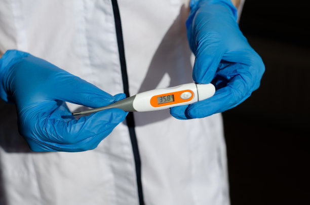一名戴着防护手套的医务人员手持电子体温计。医生给病人量体温。增加体温。医疗设备。冠状病毒感染。图片下载