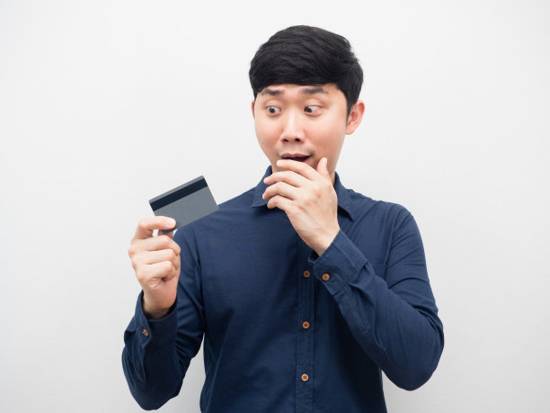 男子看着手里的信用卡感到震惊图片下载