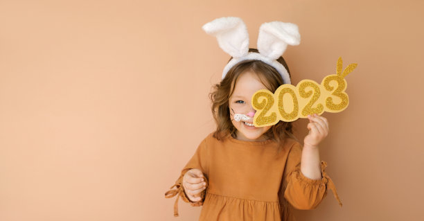 一个装扮成兔子的有趣的孩子笑着闭上了眼睛，上面写着数字2023。年份:按照东方历法的十二生肖的年份圣诞祝福的海报图片下载