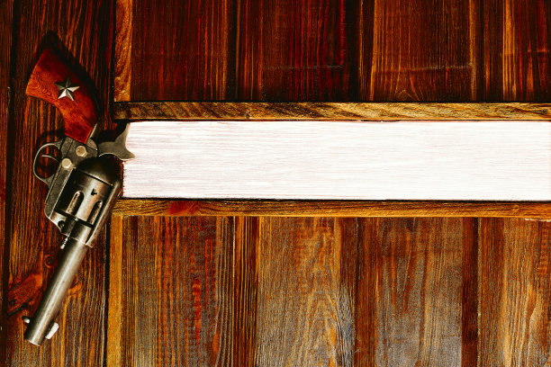 牛仔枪柯尔特左轮手枪挂在木墙与空间的文字。老板的办公室图片下载