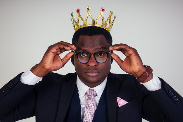 自信的商人商务国王在黑色的经典西装领带和眼镜戴在头上的皇冠在白色背景的工作室图片下载