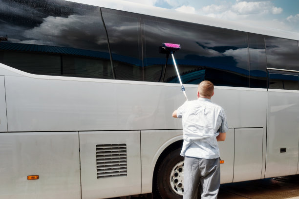 司机在夏天刷公交车的大玻璃窗。为运送旅客准备运输。图片下载