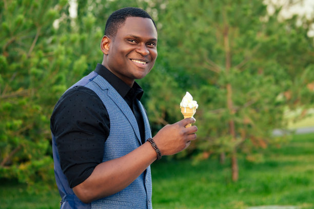 画像年轻英俊的时尚模特非洲裔美国人在一个时髦的蓝色西装在一个夏天的公园聪明的拉丁拉丁裔商人黑人家伙吃冰淇淋在华夫饼角图片下载