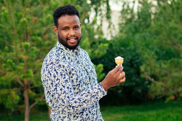 年轻英俊的时尚模特非洲裔美国人在一个时髦的蓝色西装在一个夏天的公园聪明的拉丁拉丁裔商人黑人吃甜冰淇淋在华夫饼角图片下载
