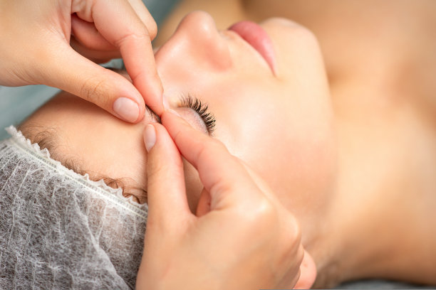 在水疗中心手工雕刻面部按摩。美容师的手指在美容院给一名年轻女子的眉毛做面部按摩，收起来。图片下载