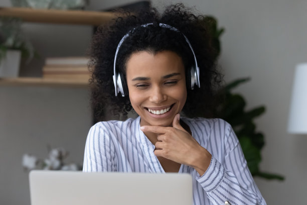 戴着耳机用笔记本电脑微笑的非裔美国妇女的头像图片下载