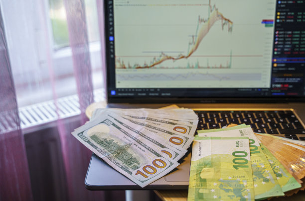 堆叠美元和欧元纸币在电脑屏幕和监视器与股票图表图片下载