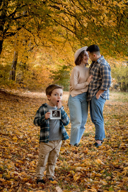一个幸福的家庭，一个男人，一个女人和一个惊讶的儿子拿着一张超声波怀孕照片。秋天的照片，一个家庭等待补充图片下载