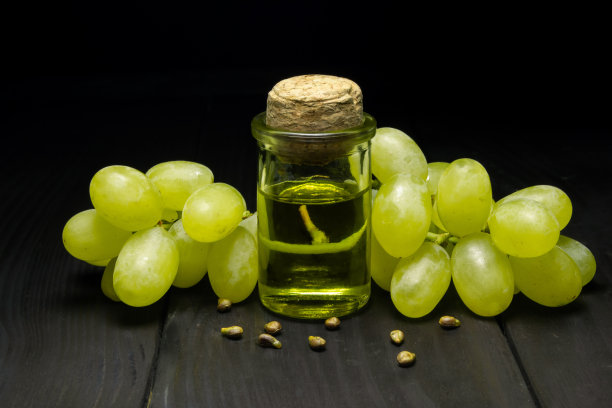 小瓶葡萄油种子。堆葡萄种子与绿色切片和冷压有机精油，酊剂，提取，输液在木制乡村背景特写图片下载