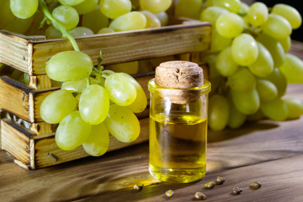 小瓶葡萄油种子。堆葡萄种子与绿色切片和冷压有机精油，酊剂，提取，输液在木制乡村背景特写图片下载