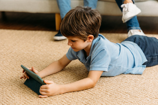 男孩躺着玩平板电脑图片下载
