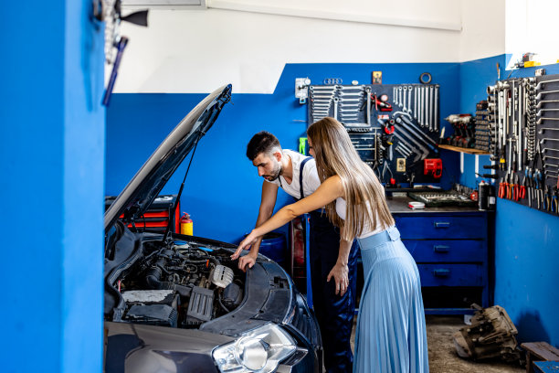 一位汽车维修工正在修理汽车，并向一位年轻女子展示问题。图片下载