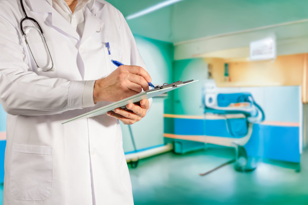 在医生办公室里，一位身穿白大褂的医生手里拿着病人的病历。背景概念为医疗诊所，保健，优质医疗，人寿保险。图片下载