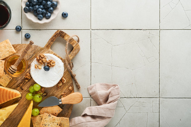 奶酪，蜂蜜，饼干，蓝莓，葡萄与红葡萄酒和白葡萄酒在玻璃杯开胃菜服务器在白色大理石板上灰色背景。奶酪片。平铺，复制空间。图片下载