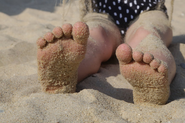 孩子的脚踩在沙滩上的沙子上。暑假在海边。图片下载