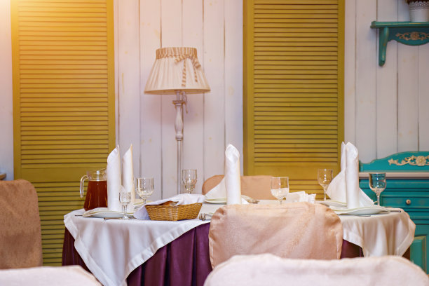 玻璃杯，花，叉子，刀提供晚餐在餐厅舒适的内部，靠近落地灯图片下载