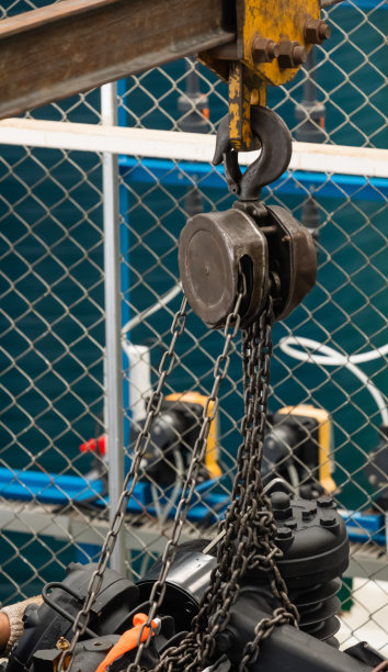 钢葫芦和棕色链条，安装在大型气泵上，准备移动和提升。用于工业使用，安全图片下载