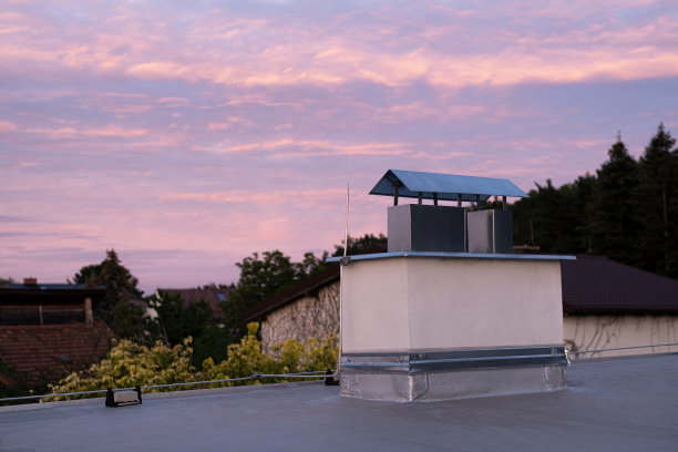 平顶覆盖沥青膜和银漆在私人住宅烟囱。私营部门的日落黄昏。图片下载