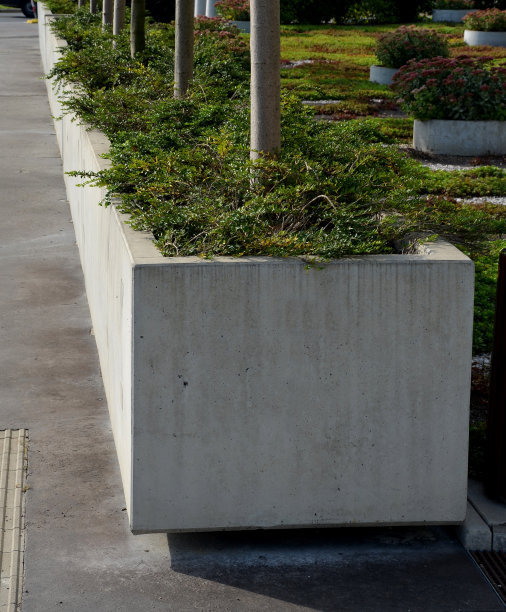 混凝土花盆，容器的形状是一个大比例的矩形或浇铸成一个拱门在街道交叉口。常绿灌木生长在地上的床层内。图片下载