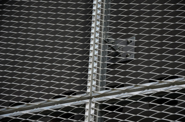 带有扩展金属网格结构的建筑物的钢包层。镀锌灰网保护工业建筑。蓝色的天空与银色的墙壁形成对比图片下载