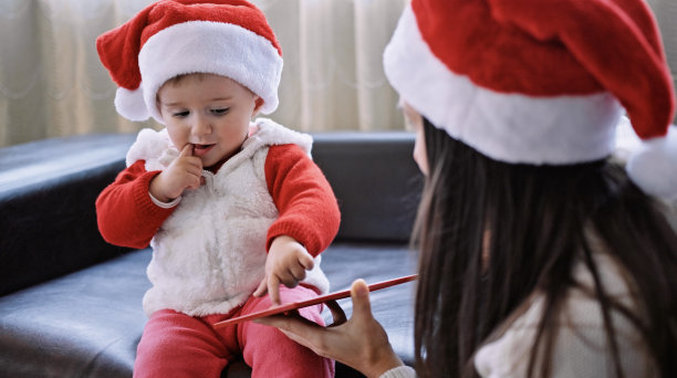 母亲带着孩子在家庆祝圣诞节。在绘图板上绘图。图片下载