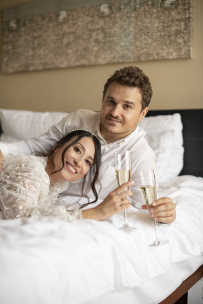 新婚夫妇在床上用香槟杯敬酒图片下载