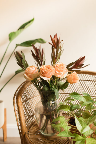 软桃色乡村玫瑰与锈色秋叶插在波西米亚藤椅上的花瓶里图片下载