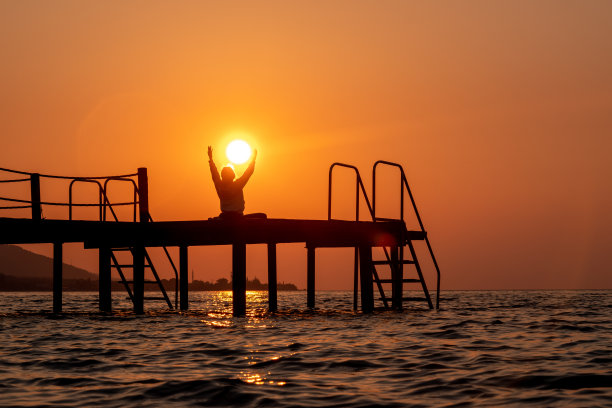 日出时分，一名女子独自在码头上练习瑜伽图片下载
