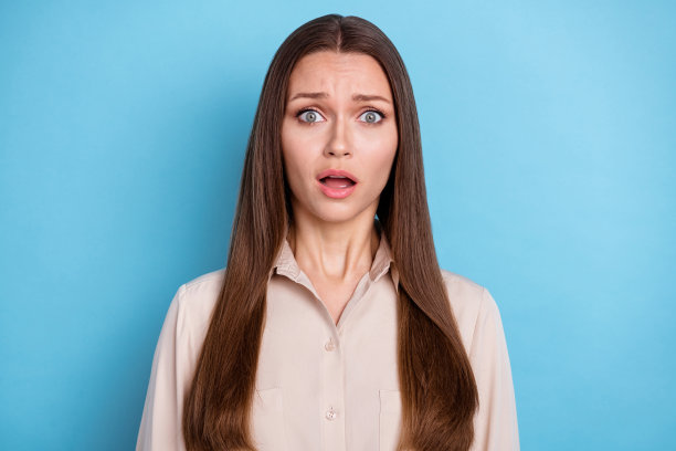照片华丽的害怕漂亮的女人长发打扮米色衬衫盯着相机孤立的蓝色背景图片下载