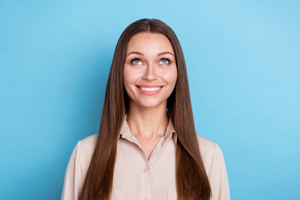 照片漂亮乐观开朗的女人长发穿米色衬衫看着空空间孤立在蓝色背景图片下载