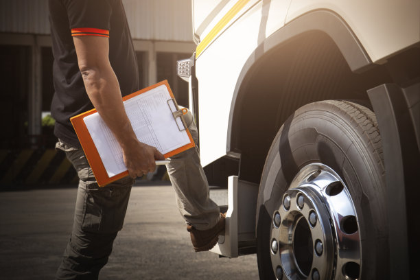 卡车司机手持剪贴板检查卡车车轮轮胎。维护检查表。卡车检查及安全驾驶。货运卡车运输。图片下载