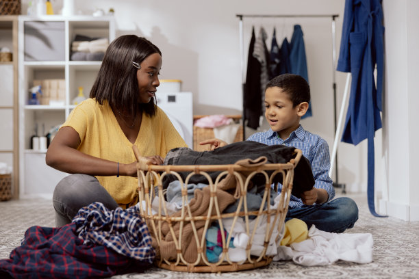 儿子帮助母亲做家务，妇女们分类衣物，叠衣服，准备晾晒，他们一起在浴室里微笑着聊天图片下载