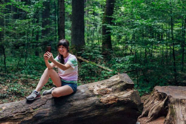 年轻爱冒险的女子正在森林里自拍图片下载