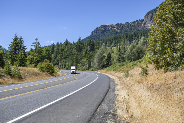 专业的白色大钻机半挂车牵引车和半挂车在拐弯的高速公路上运行，在风景秀丽的自然野生哥伦比亚峡谷地区图片下载