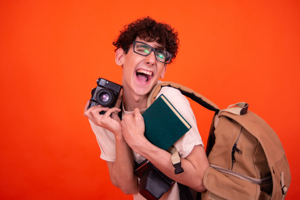 年轻迷人的背包游客。橙色背景。图片下载