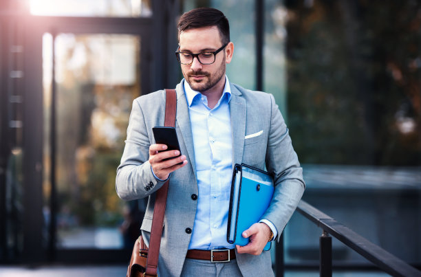 成功的商人站在公司前面，用智能手机查看数据。商业，教育，生活理念图片下载