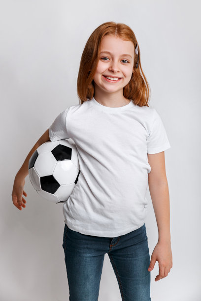 可爱的小孩梦想成为一名足球运动员。红发女孩踢足球。图片下载