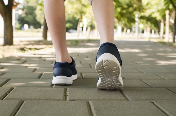 在一个阳光明媚的日子里，一个穿着运动鞋的孩子走在人行道上图片下载