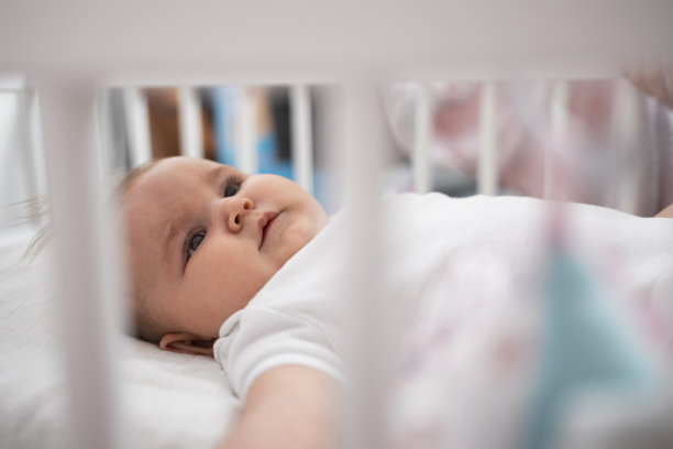 一张透过婴儿床栏杆的婴儿照片。图片下载